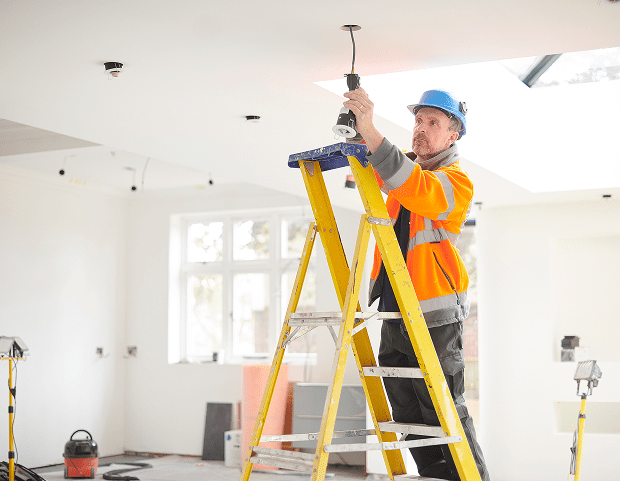 Construction worker on ladder installing lights