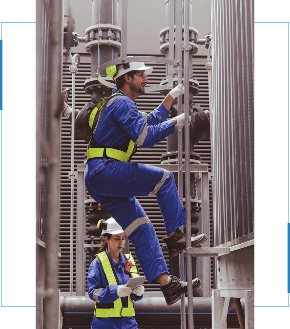 Electricians in safety gear working on equipment, one climbing a ladder while the other reviews a document, highlighting teamwork in the electrical industry.